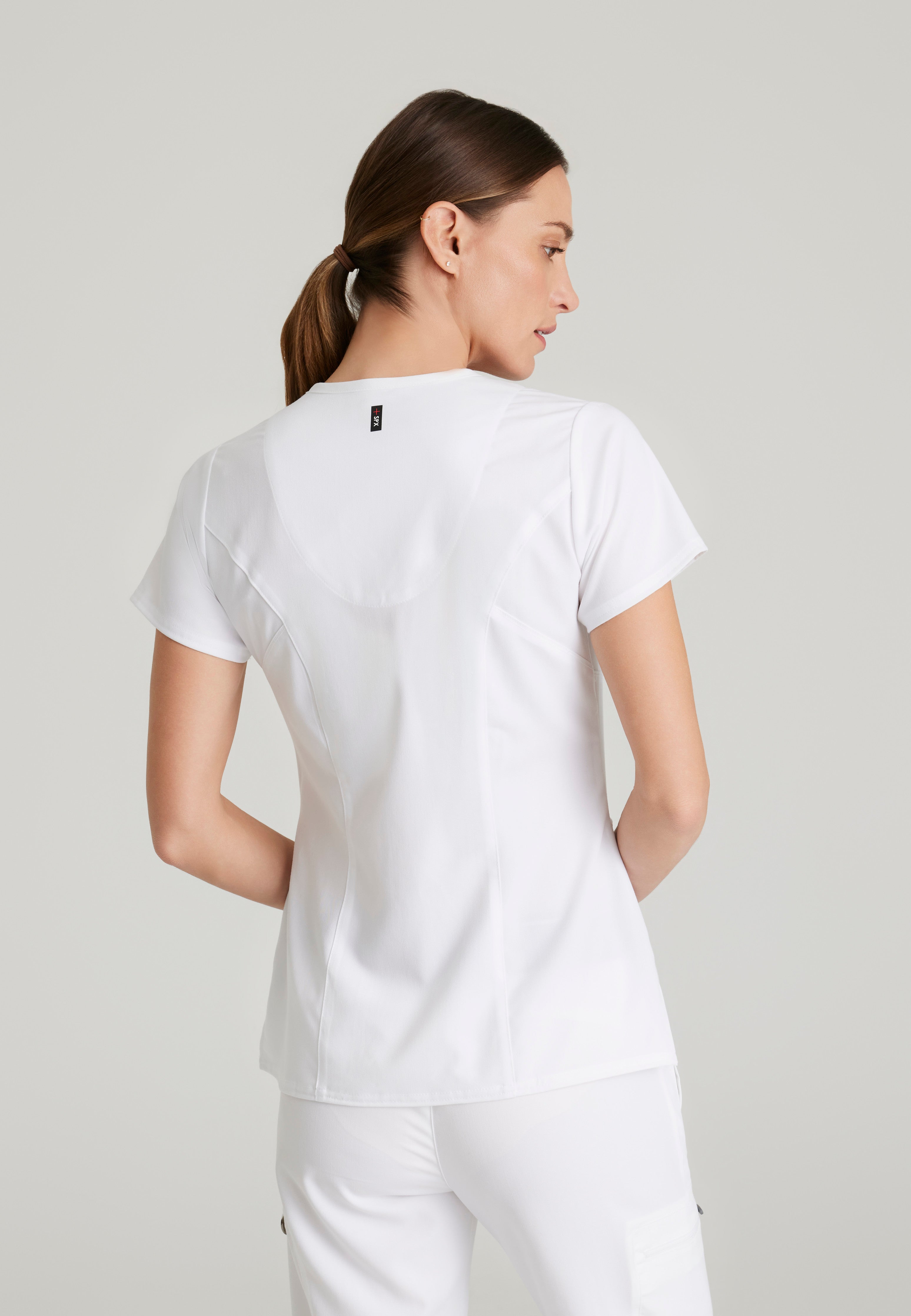 Back View of the Kim 3-Pocket Crossover V-Neck Scrub Top in White from Grey's Anatomy™ by Barco Spandex Stretch