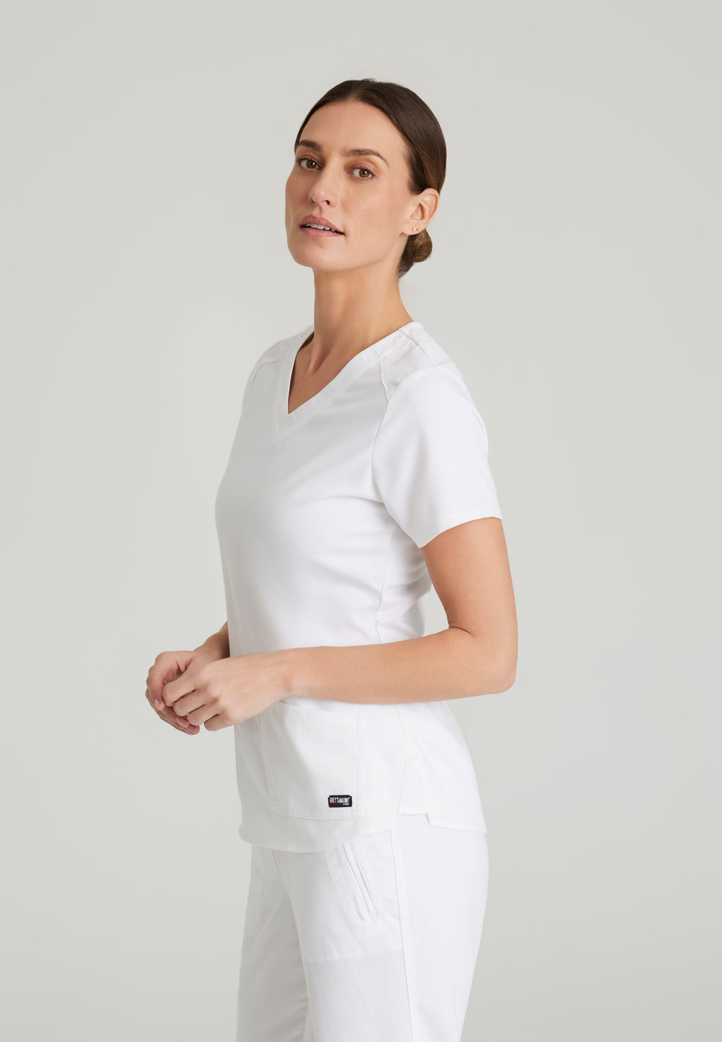 Side View of the Emma 4-Pocket V-Neck Scrub Top in White from Grey's Anatomy™ by Barco Spandex Stretch