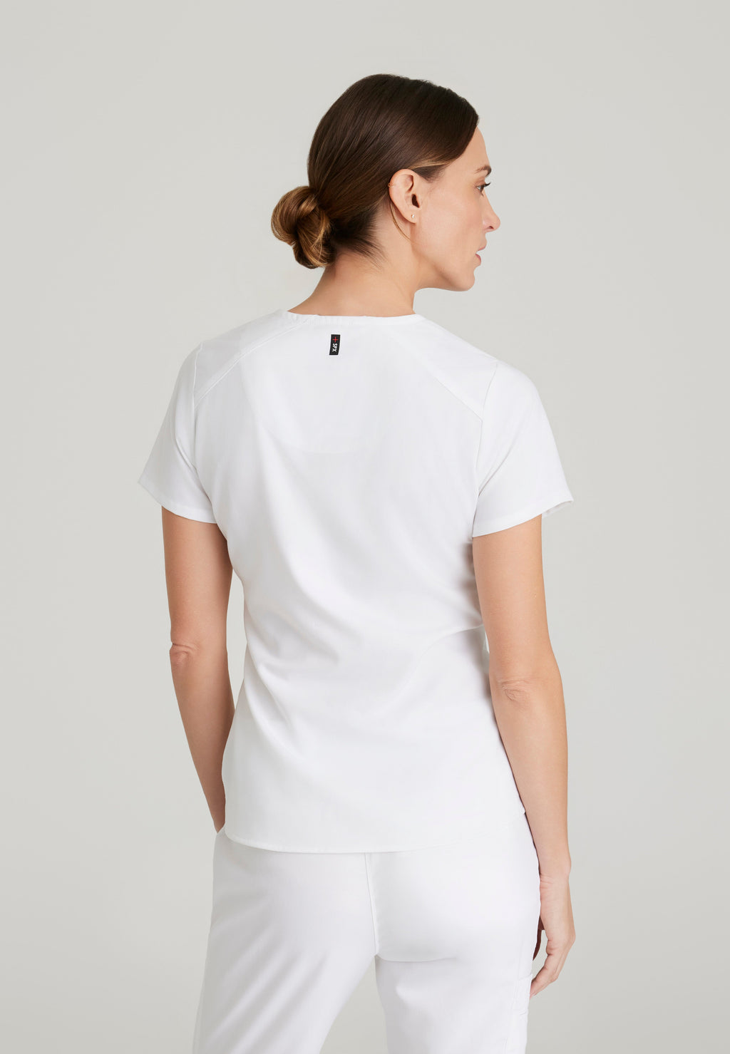 Back View of the Emma 4-Pocket V-Neck Scrub Top in White from Grey's Anatomy™ by Barco Spandex Stretch