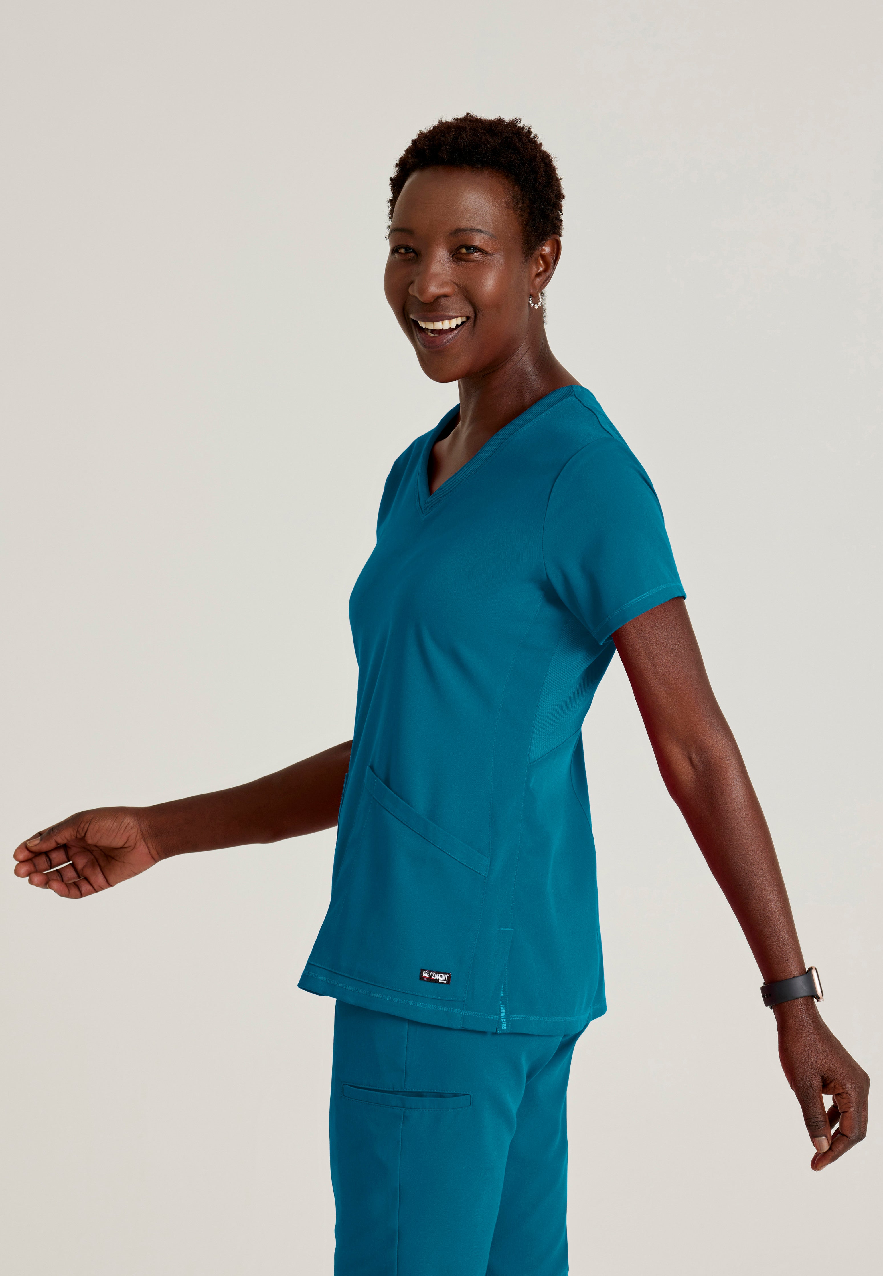 Side View of the Serena 3-Pocket Curved V-Neck Scrub Top in Bahama from Grey's Anatomy™ by Barco Spandex Stretch