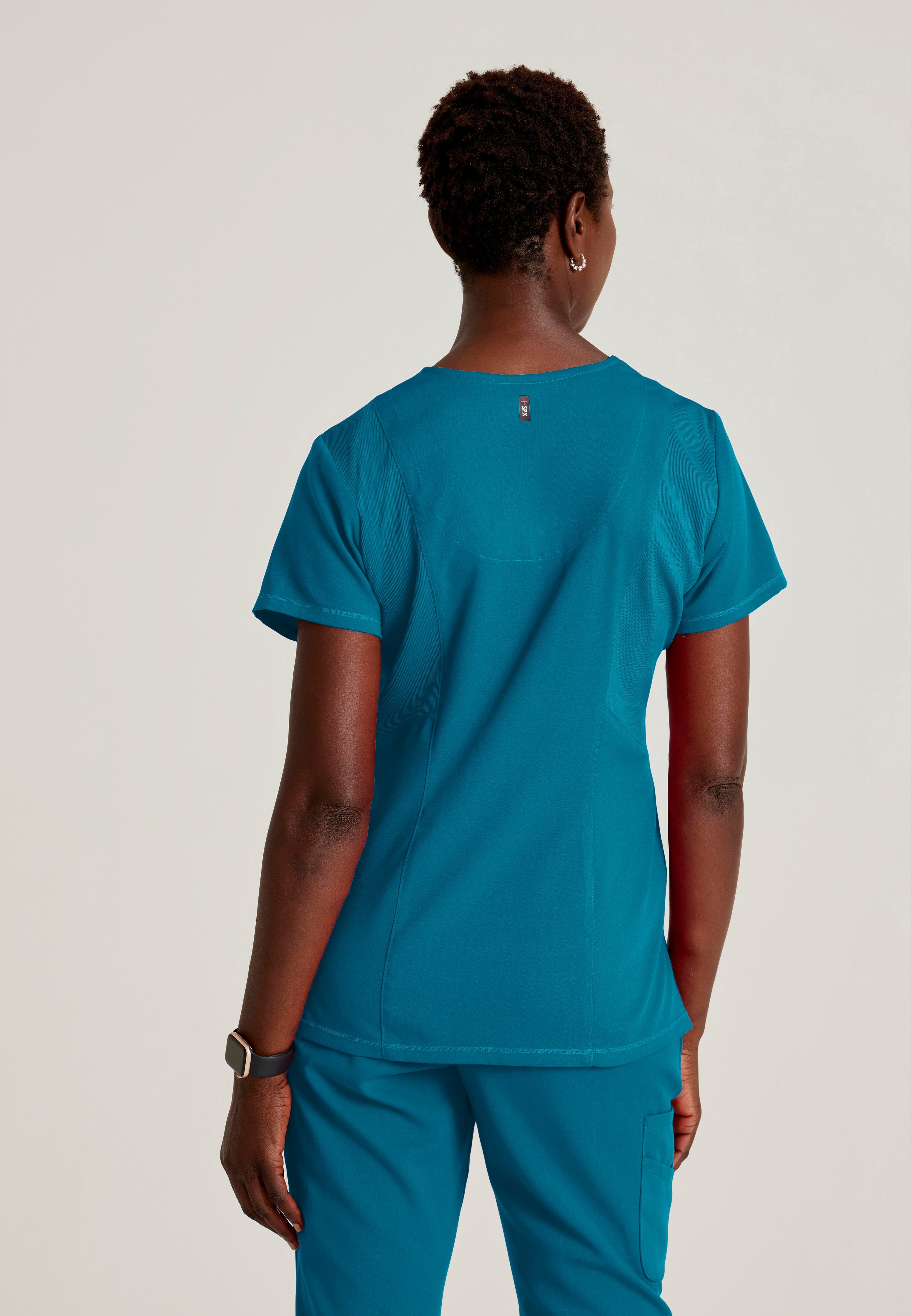 Back View of the Serena 3-Pocket Curved V-Neck Scrub Top in Bahama from Grey's Anatomy™ by Barco Spandex Stretch