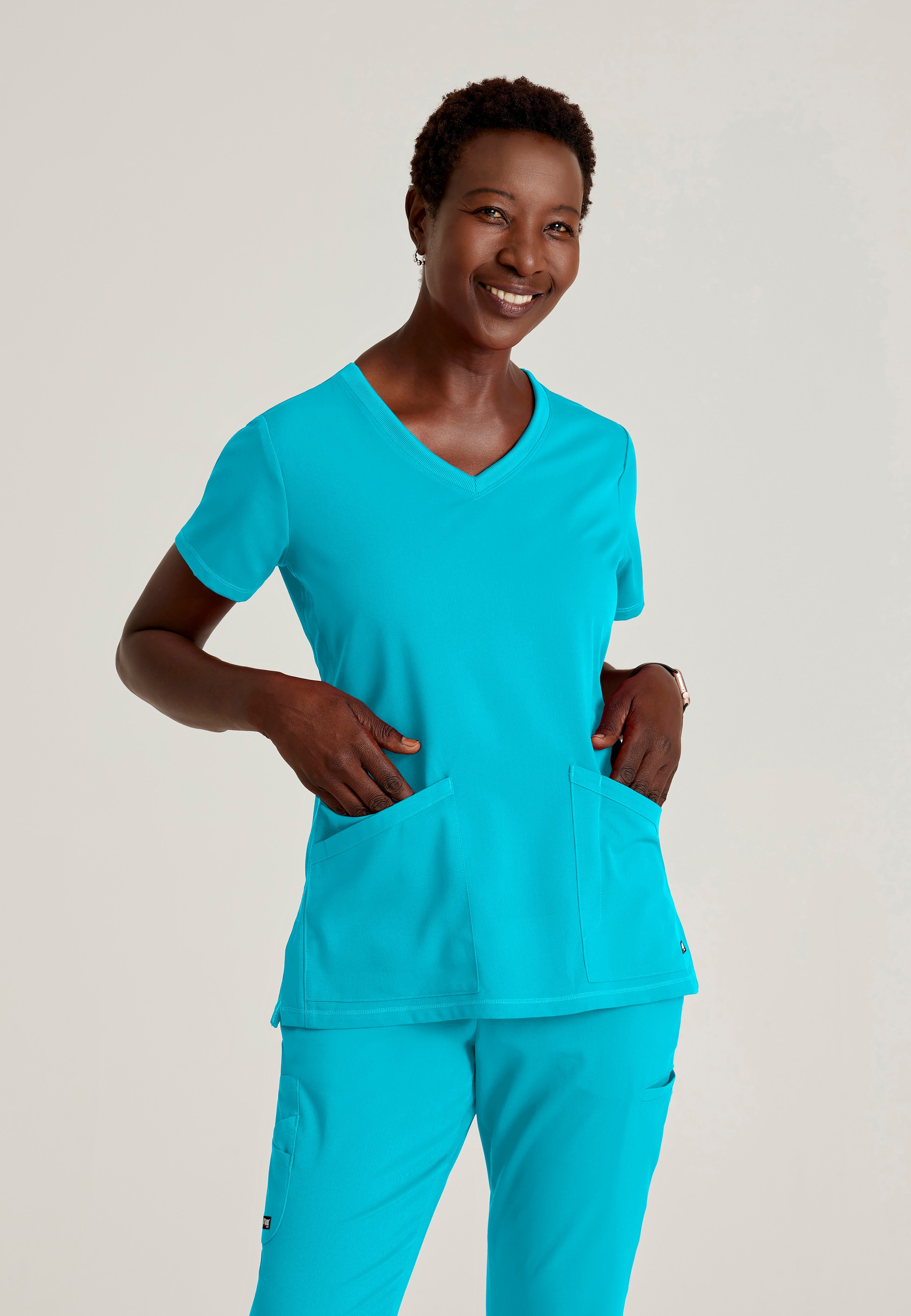 Front View of the Serena 3-Pocket Curved V-Neck Scrub Top in Teal from Grey's Anatomy™ by Barco Spandex Stretch