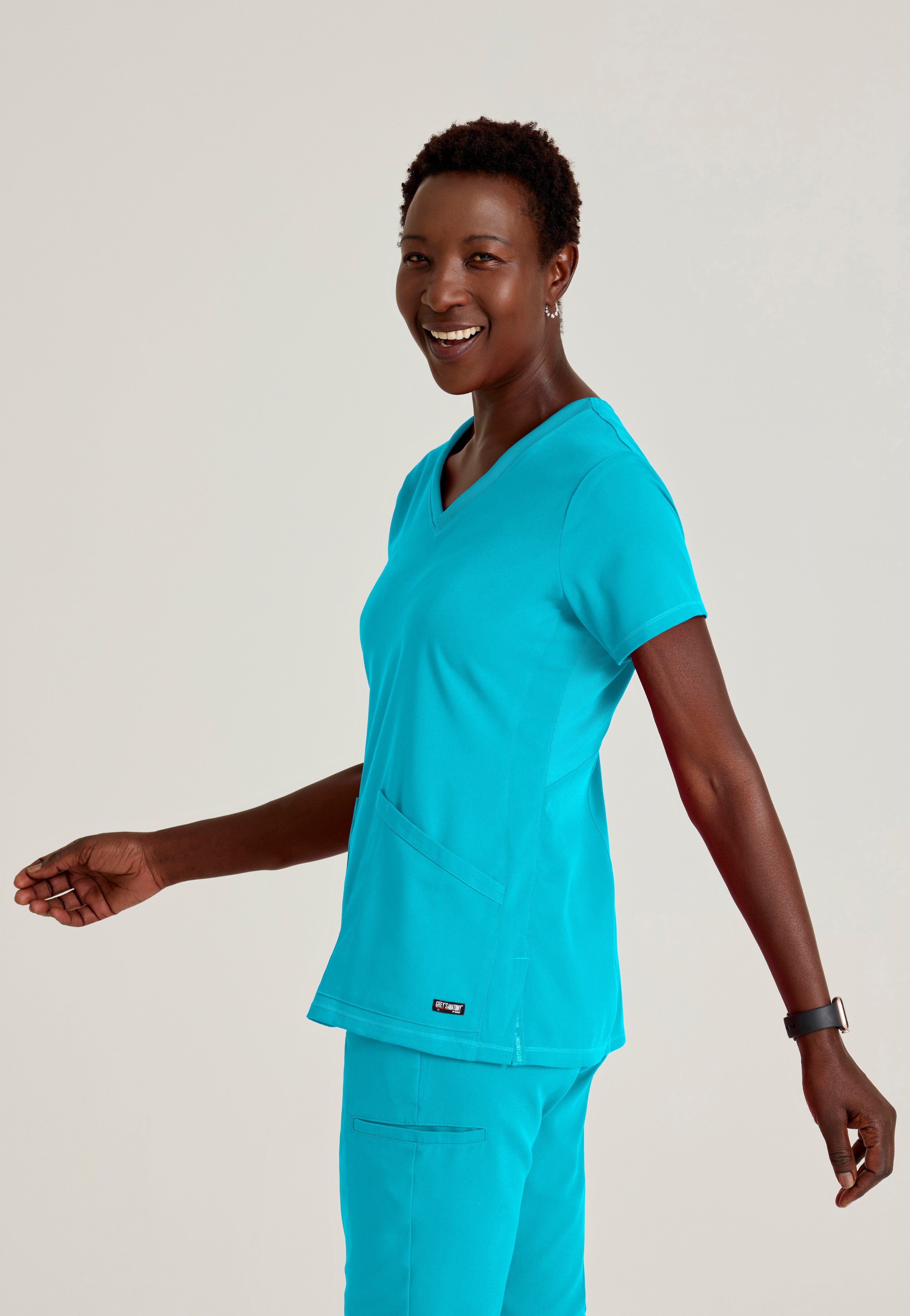 Side View of the Serena 3-Pocket Curved V-Neck Scrub Top in Teal from Grey's Anatomy™ by Barco Spandex Stretch