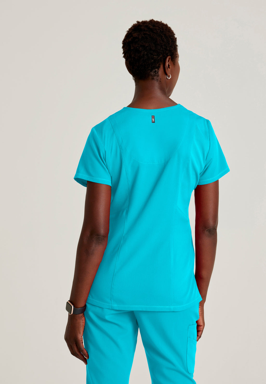 Back View of the Serena 3-Pocket Curved V-Neck Scrub Top in Teal from Grey's Anatomy™ by Barco Spandex Stretch