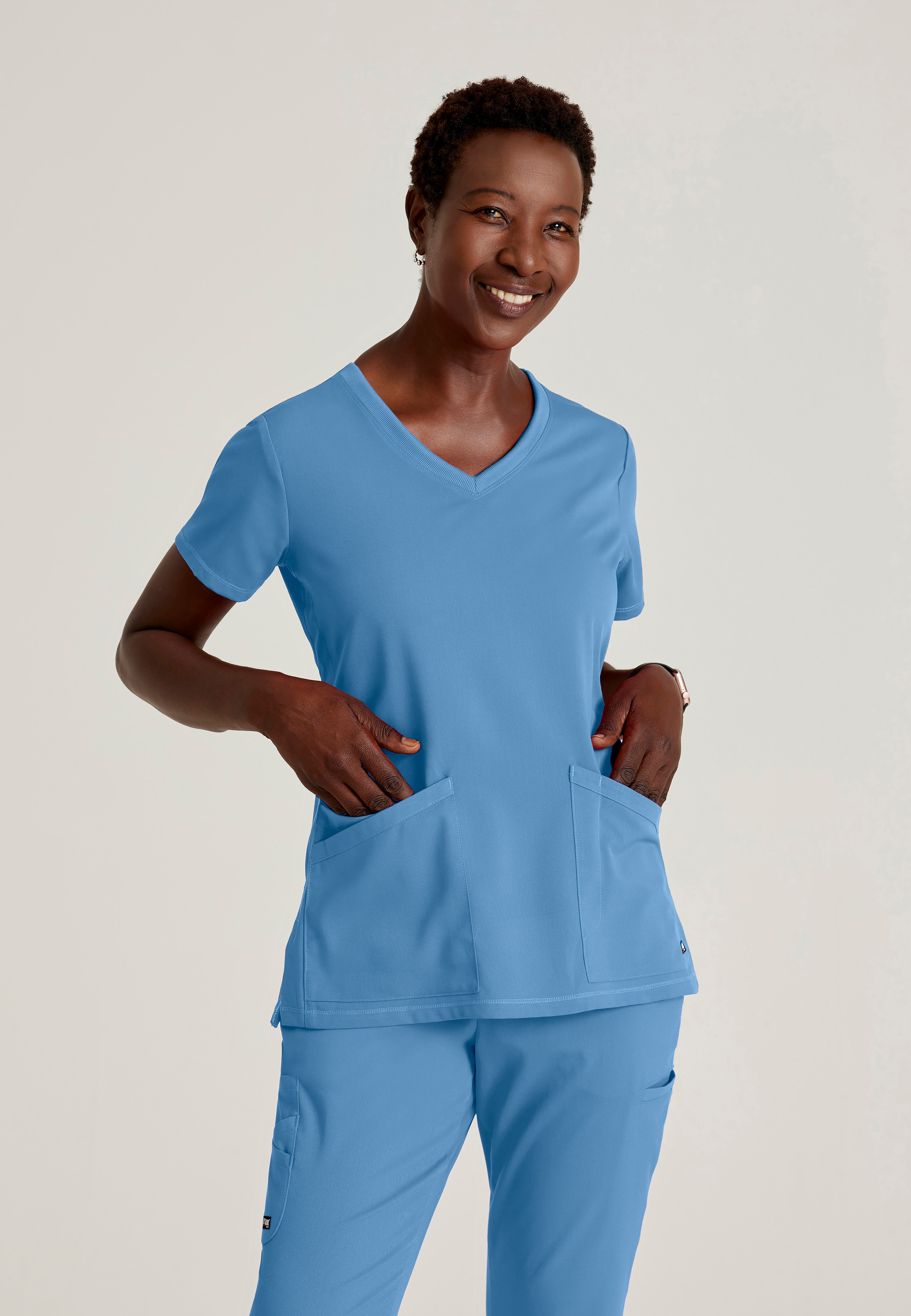Front View of the Serena 3-Pocket Curved V-Neck Scrub Top in Ciel Blue from Grey's Anatomy™ by Barco Spandex Stretch