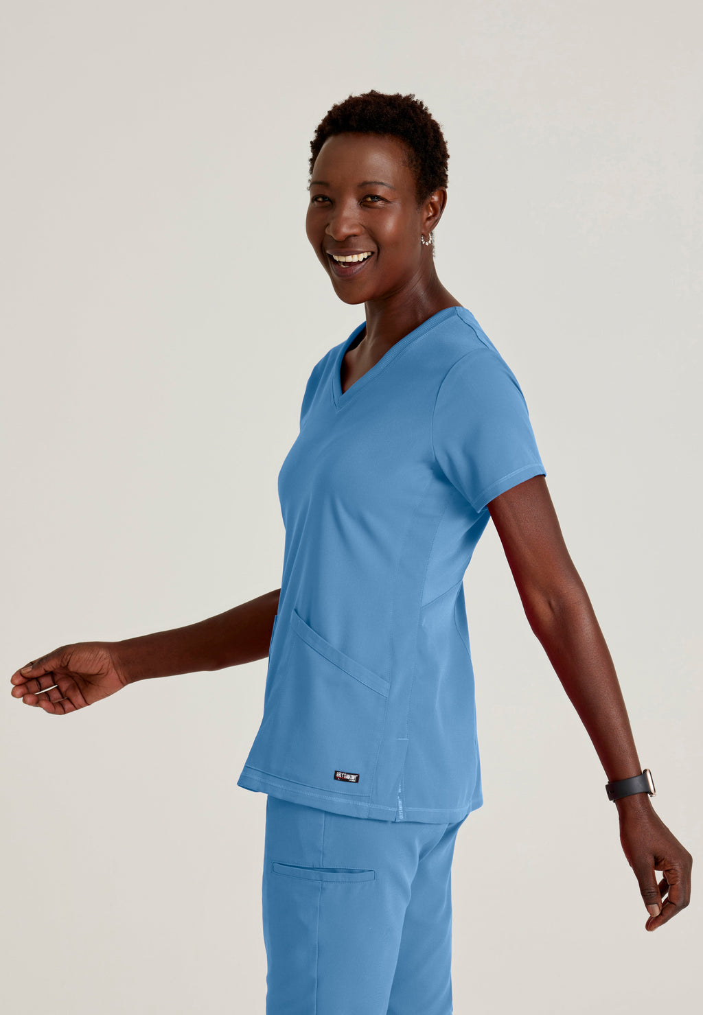 Side View of the Serena 3-Pocket Curved V-Neck Scrub Top in Ciel Blue from Grey's Anatomy™ by Barco Spandex Stretch
