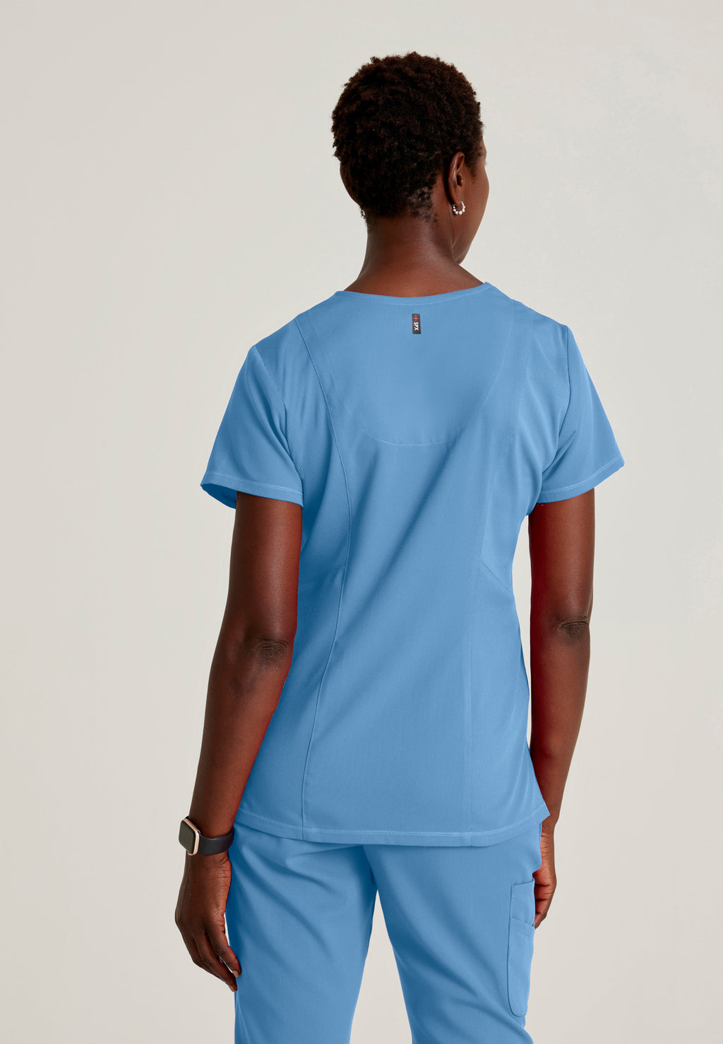 Back View of the Serena 3-Pocket Curved V-Neck Scrub Top in Ciel Blue from Grey's Anatomy™ by Barco Spandex Stretch