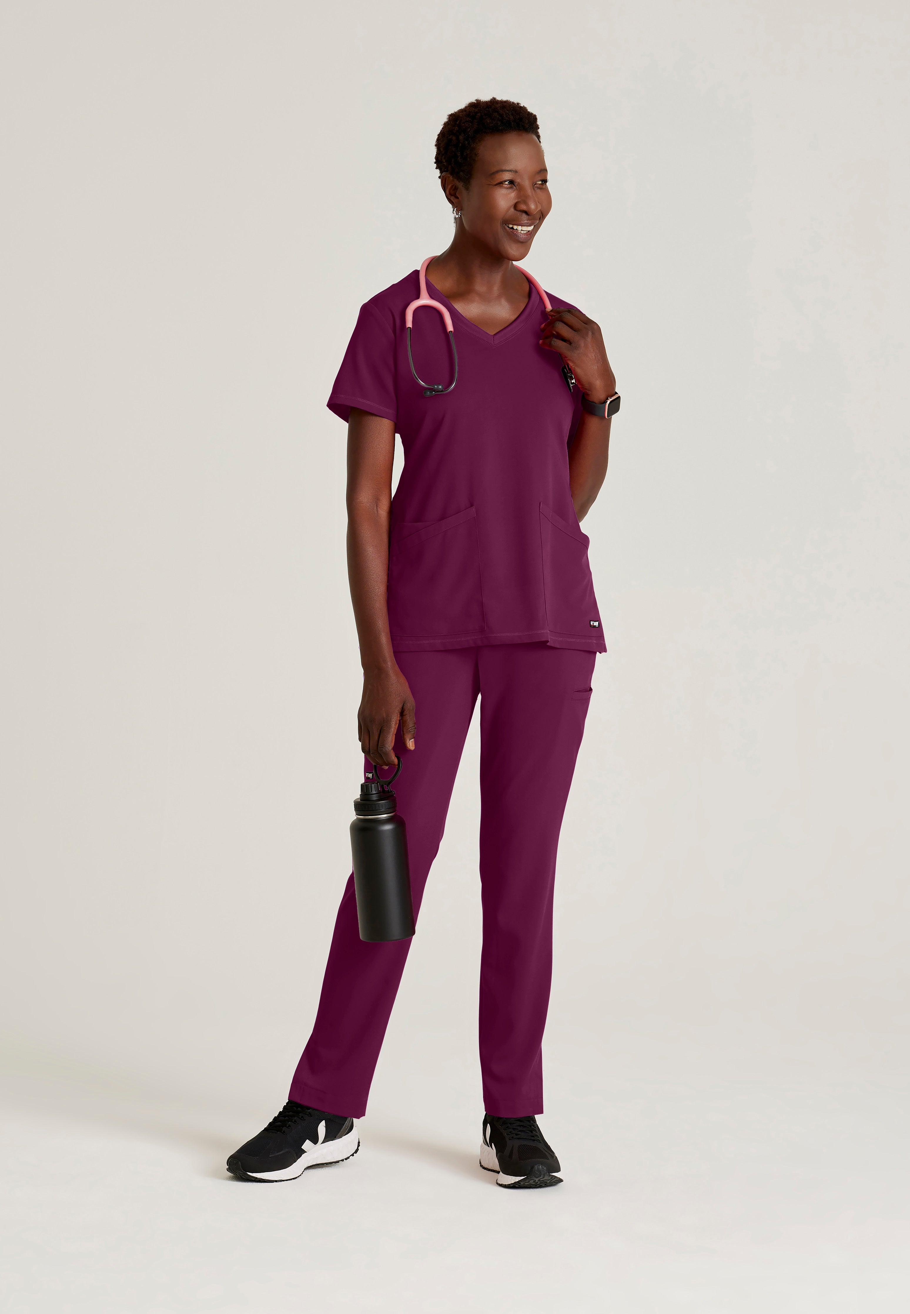 Full Body View of the Serena 3-Pocket Curved V-Neck Scrub Top in Wine from Grey's Anatomy™ by Barco Spandex Stretch