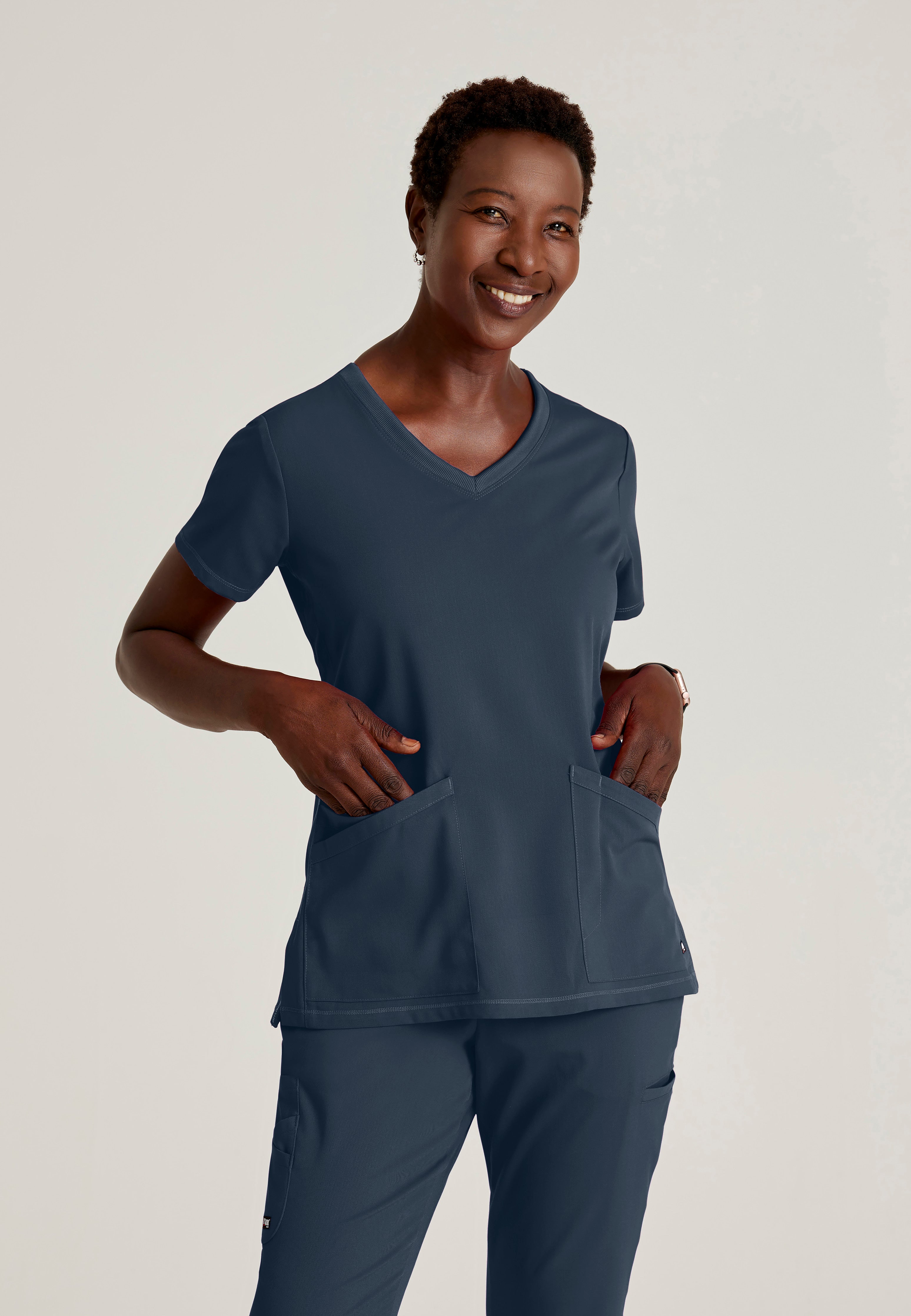 Front View of the Serena 3-Pocket Curved V-Neck Scrub Top in Steel from Grey's Anatomy™ by Barco Spandex Stretch