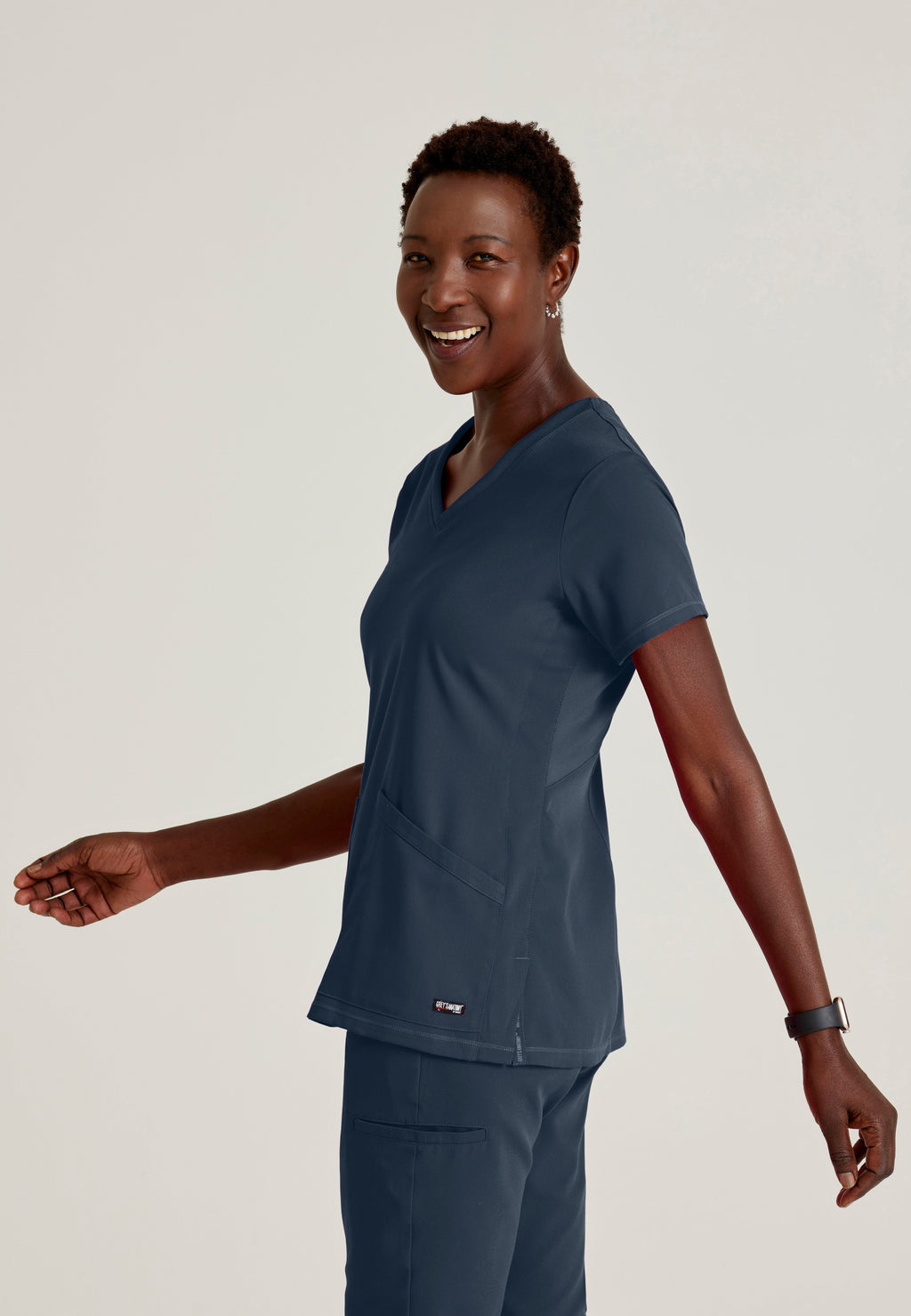 Side View of the Serena 3-Pocket Curved V-Neck Scrub Top in Steel from Grey's Anatomy™ by Barco Spandex Stretch