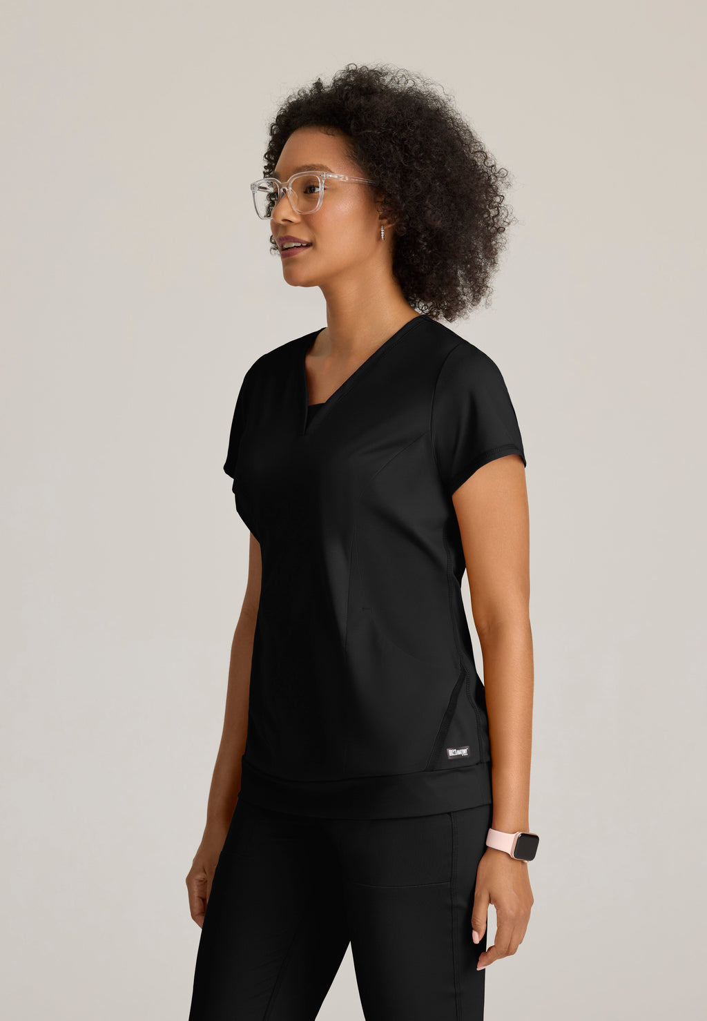 Side View of the Motivate Curved V-Neck Knit Scrub Top in Black from Grey's Anatomy™ by Barco Knit Stretch