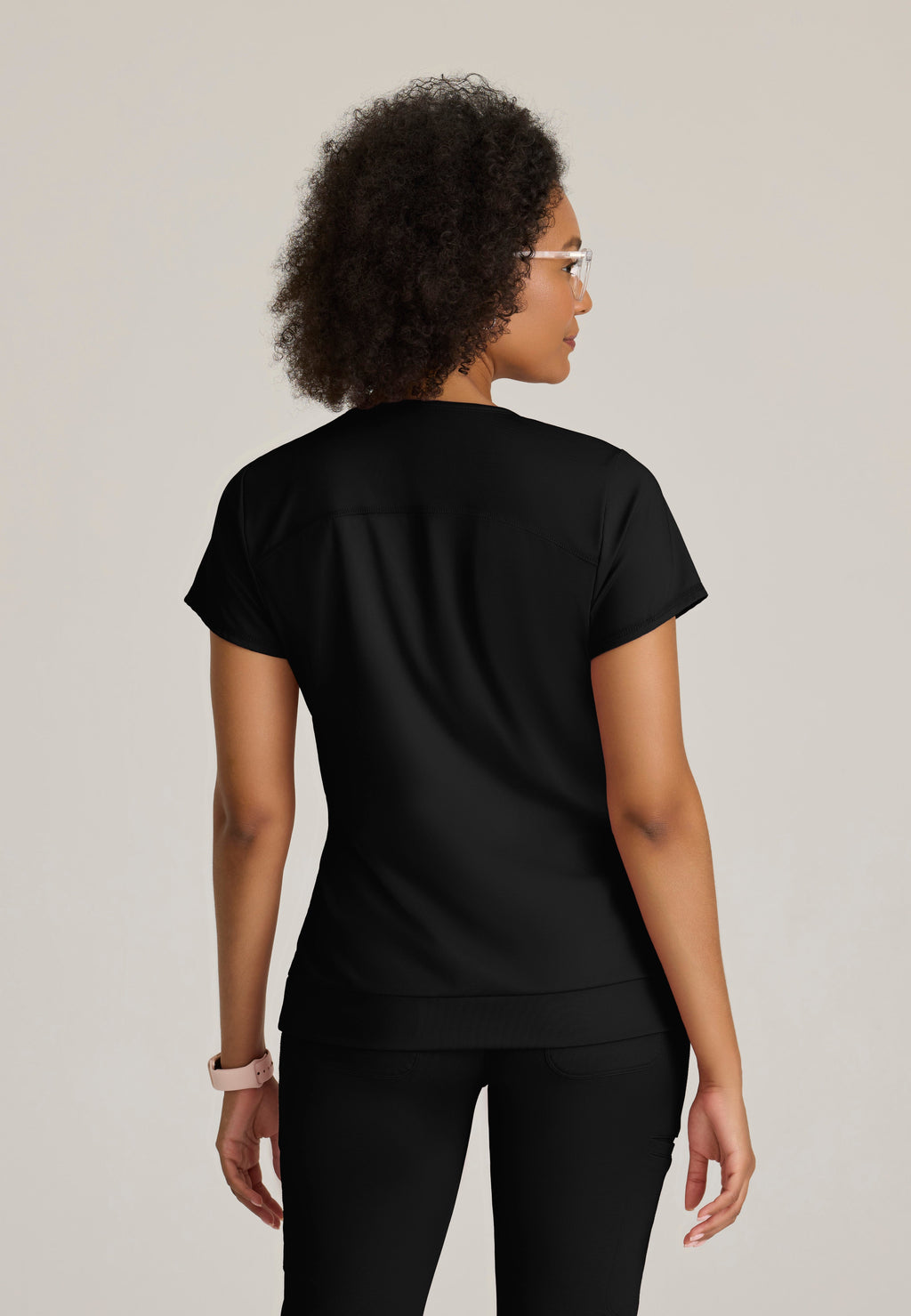 Back View of the Motivate Curved V-Neck Knit Scrub Top in Black from Grey's Anatomy™ by Barco Knit Stretch