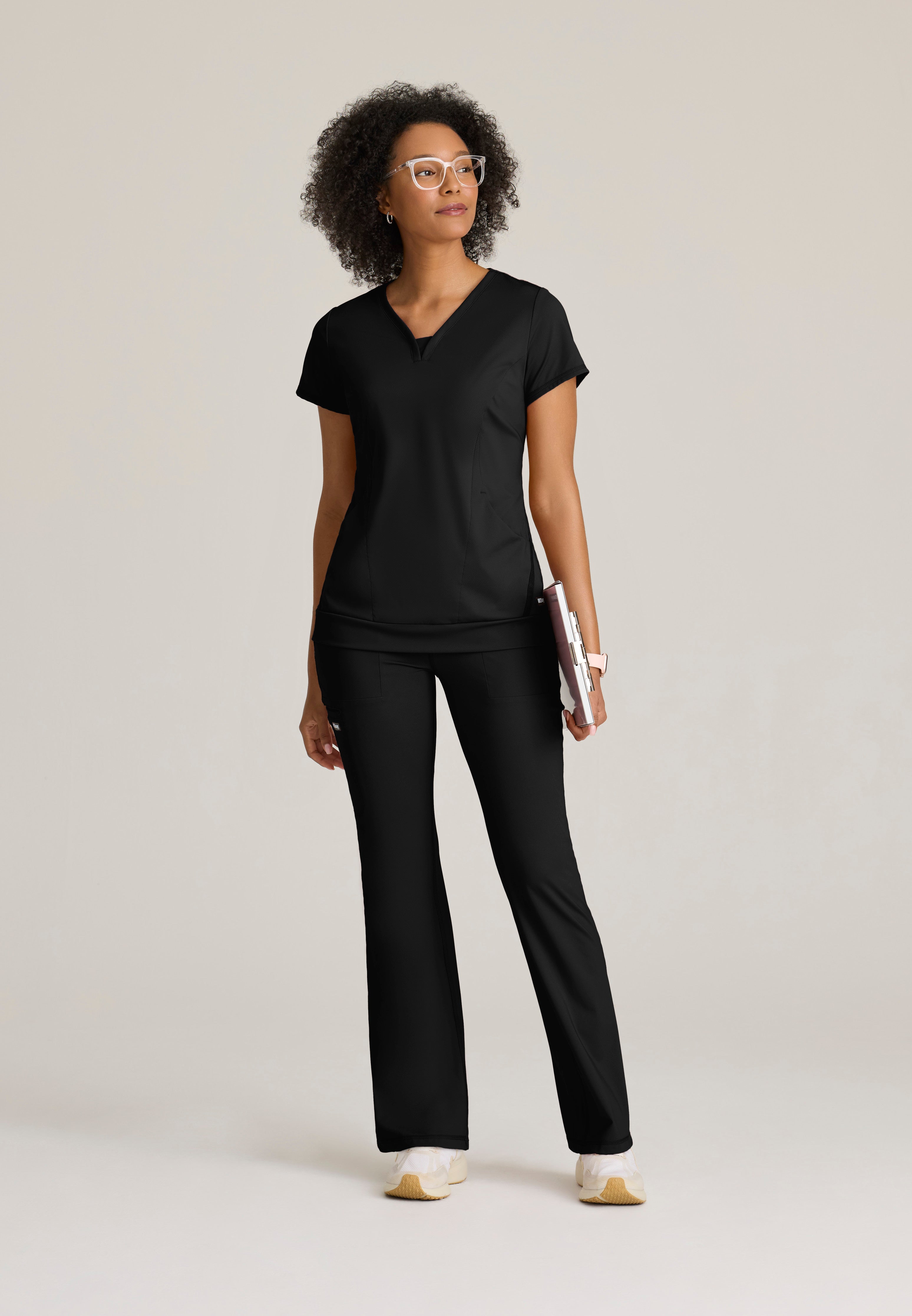 Full Body View of the Motivate Curved V-Neck Knit Scrub Top in Black from Grey's Anatomy™ by Barco Knit Stretch
