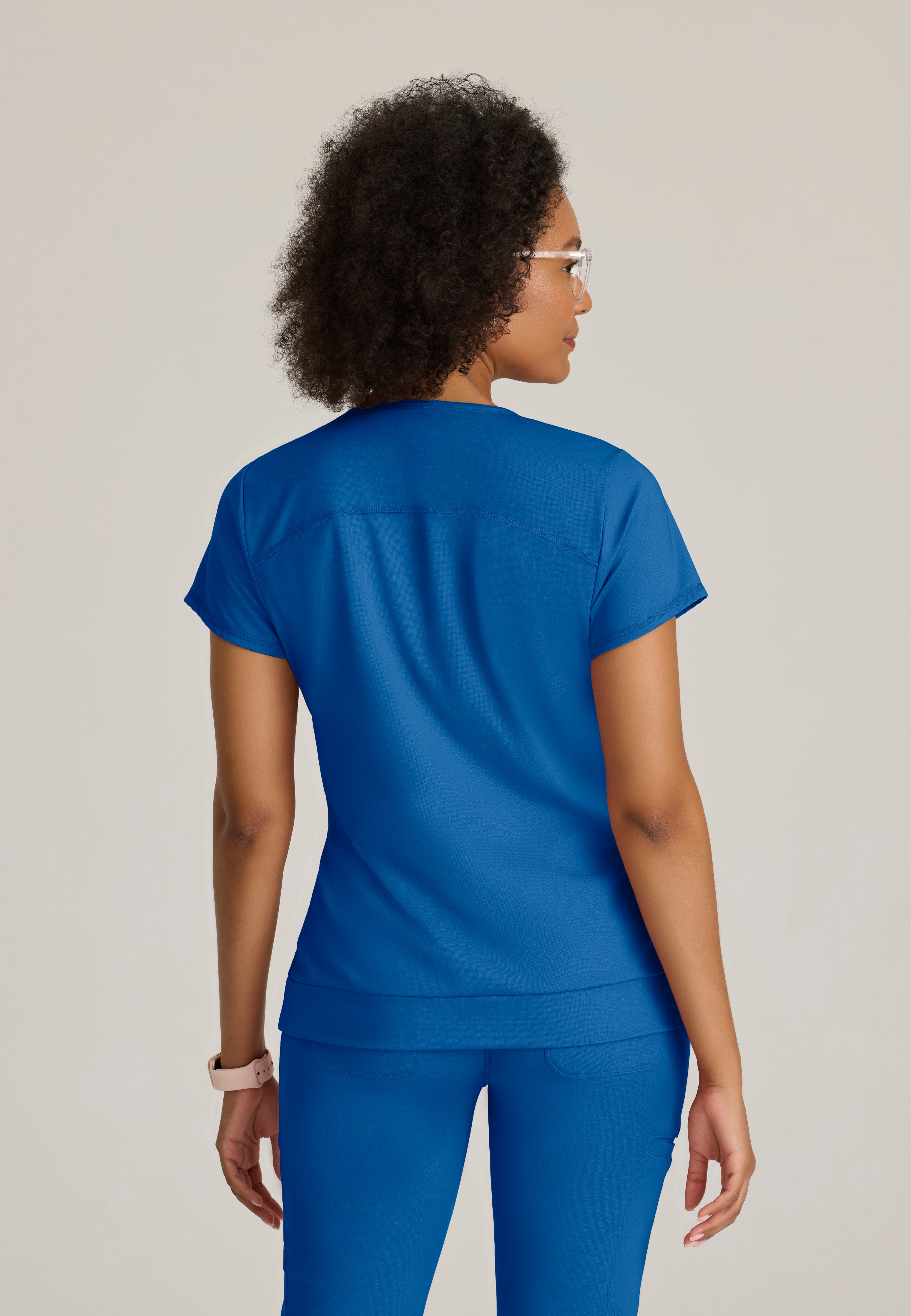 Back View of the Motivate Curved V-Neck Knit Scrub Top in New Royal from Grey's Anatomy™ by Barco Knit Stretch