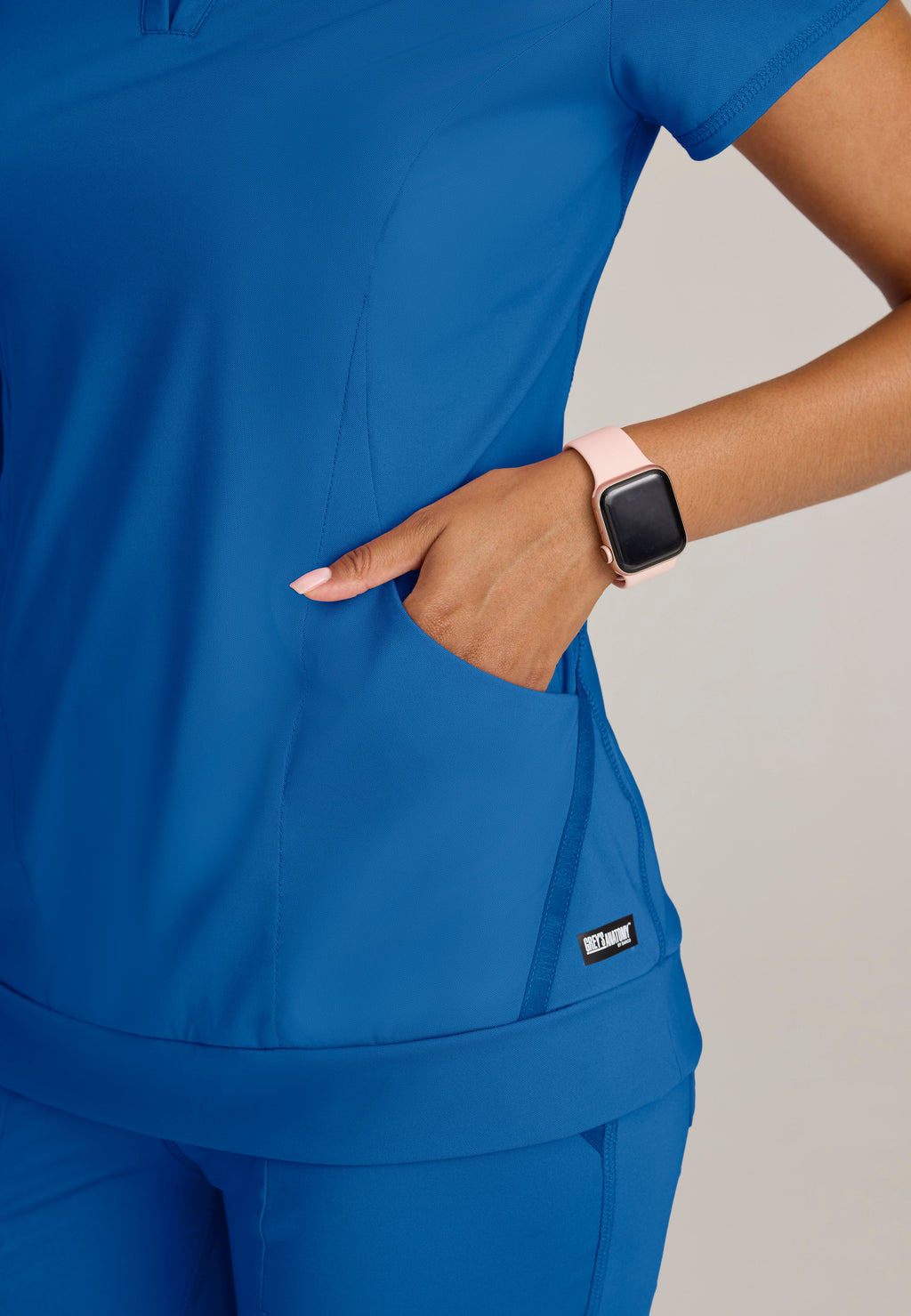 Detail Shot of the Motivate Curved V-Neck Knit Scrub Top in New Royal from Grey's Anatomy™ by Barco Knit Stretch