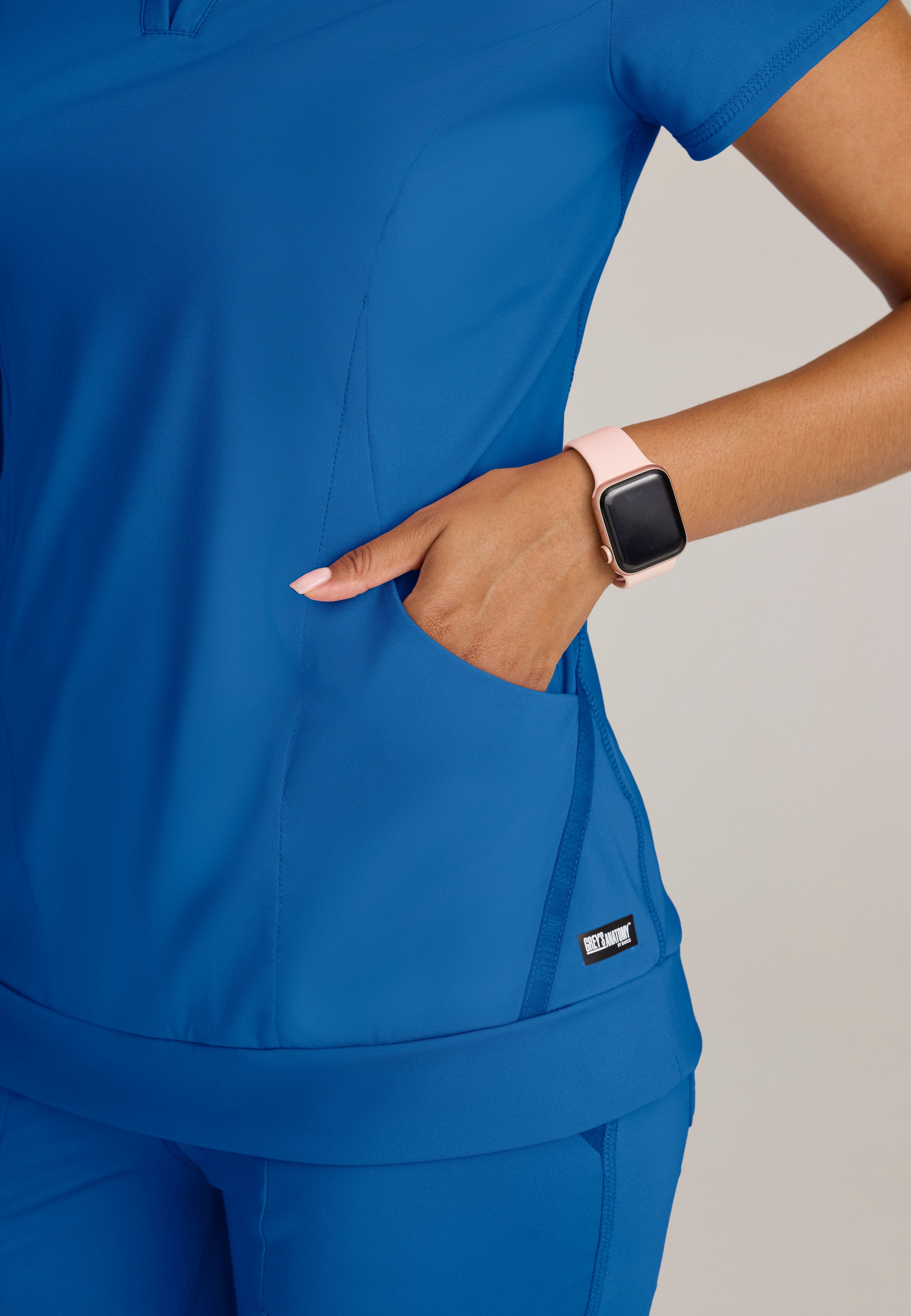 Detail Shot of the Motivate Curved V-Neck Knit Scrub Top in New Royal from Grey's Anatomy™ by Barco Knit Stretch