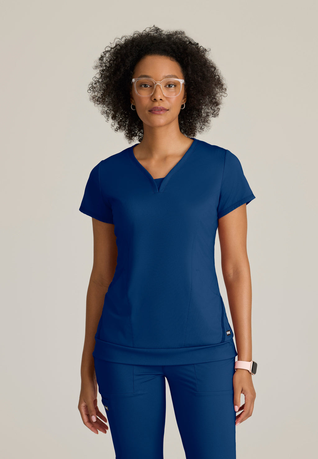 Front View of the Motivate Curved V-Neck Knit Scrub Top in Indigo from Grey's Anatomy™ by Barco Knit Stretch