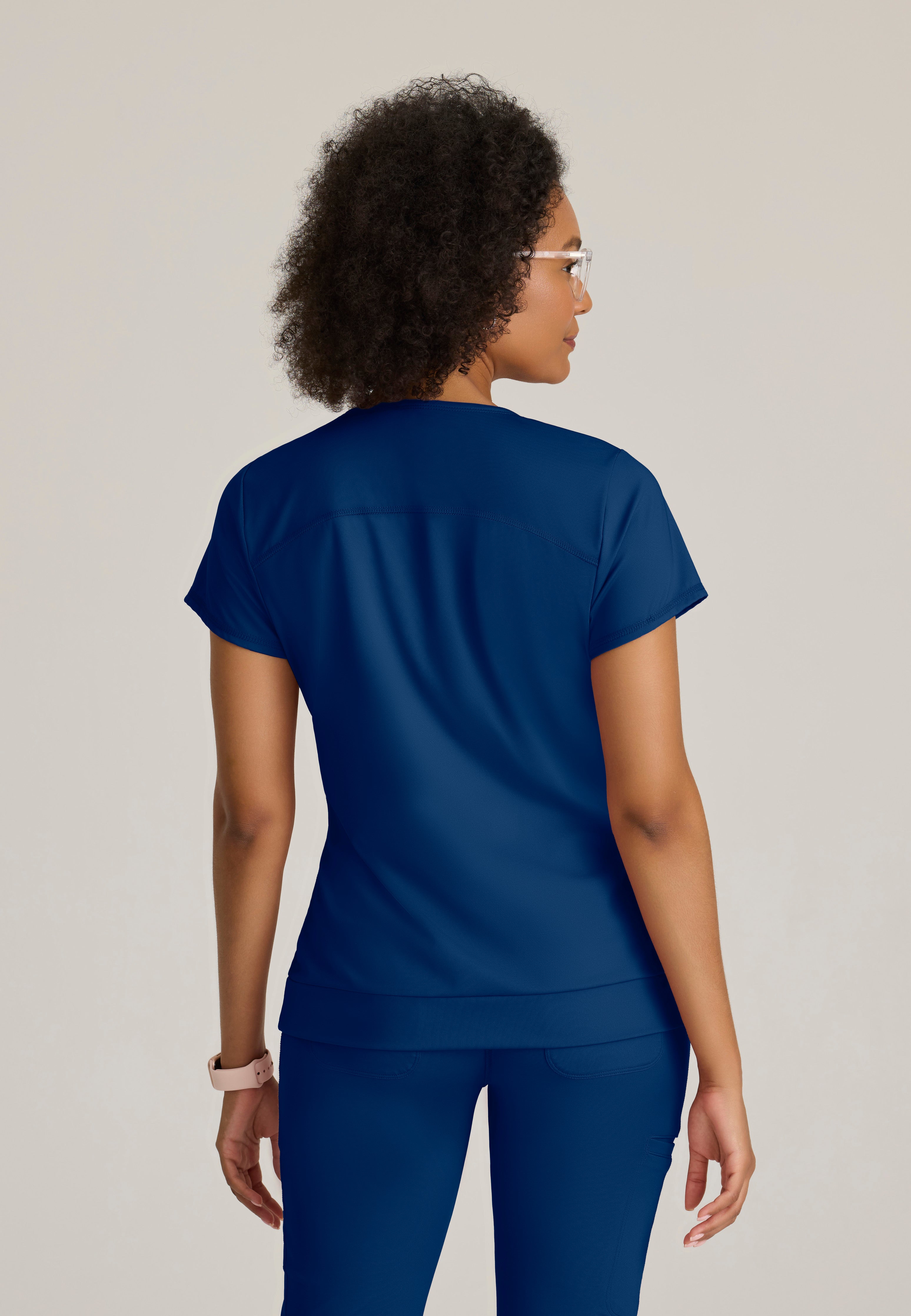 Back View of the Motivate Curved V-Neck Knit Scrub Top in Indigo from Grey's Anatomy™ by Barco Knit Stretch