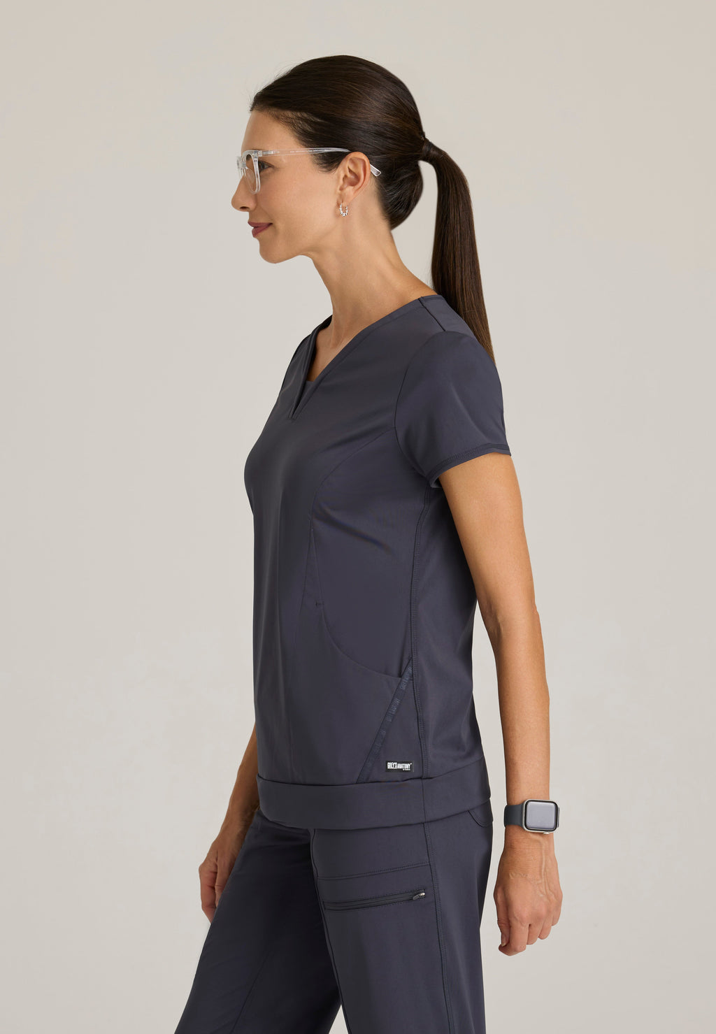 Side View of the Motivate Curved V-Neck Knit Scrub Top in Steel from Grey's Anatomy™ by Barco Knit Stretch