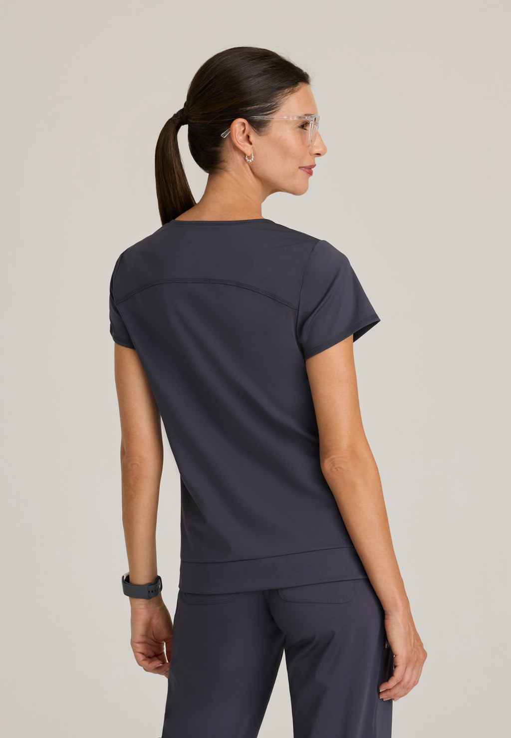 Back View of the Motivate Curved V-Neck Knit Scrub Top in Steel from Grey's Anatomy™ by Barco Knit Stretch