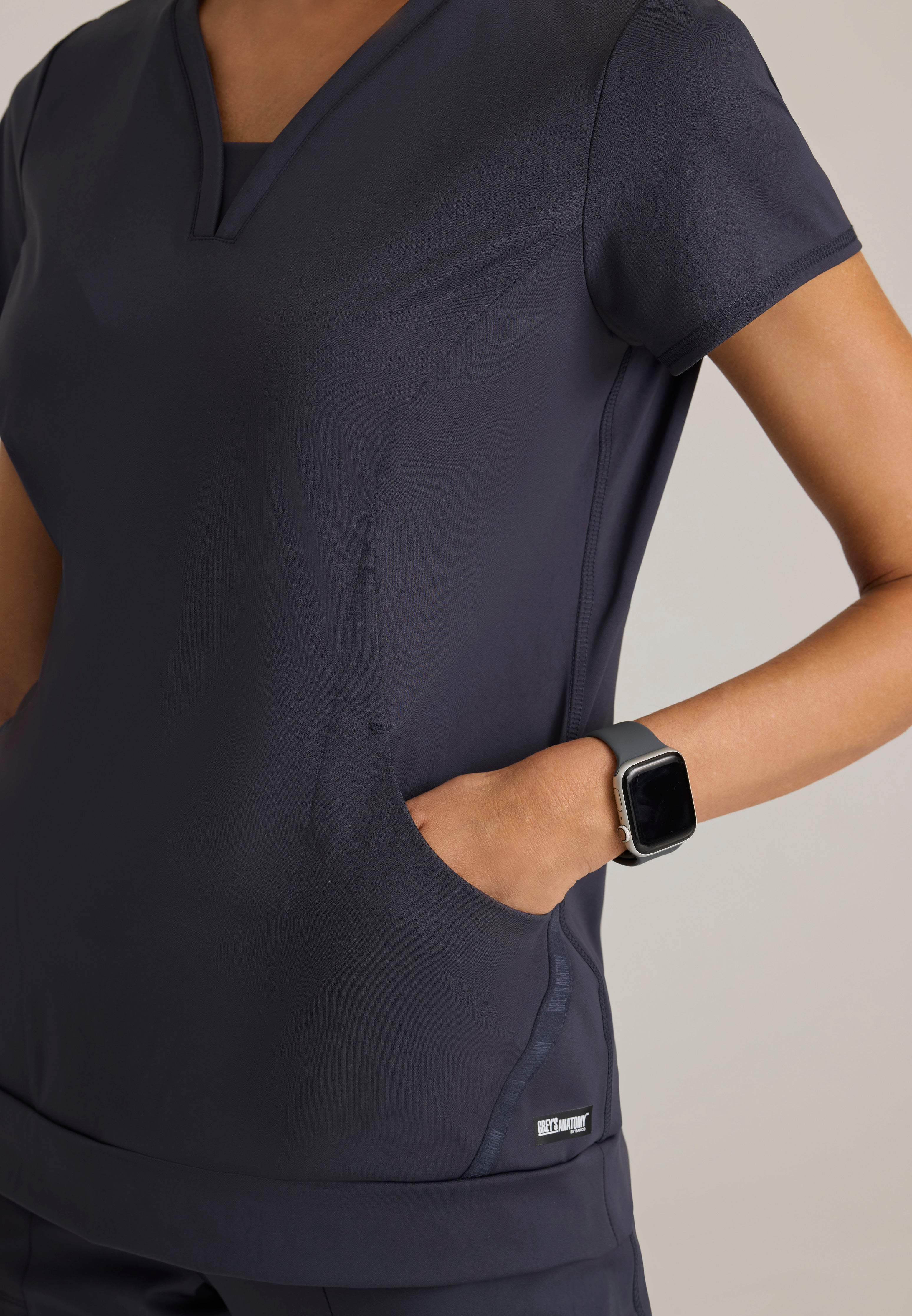 Detail Shot of the Motivate Curved V-Neck Knit Scrub Top in Steel from Grey's Anatomy™ by Barco Knit Stretch
