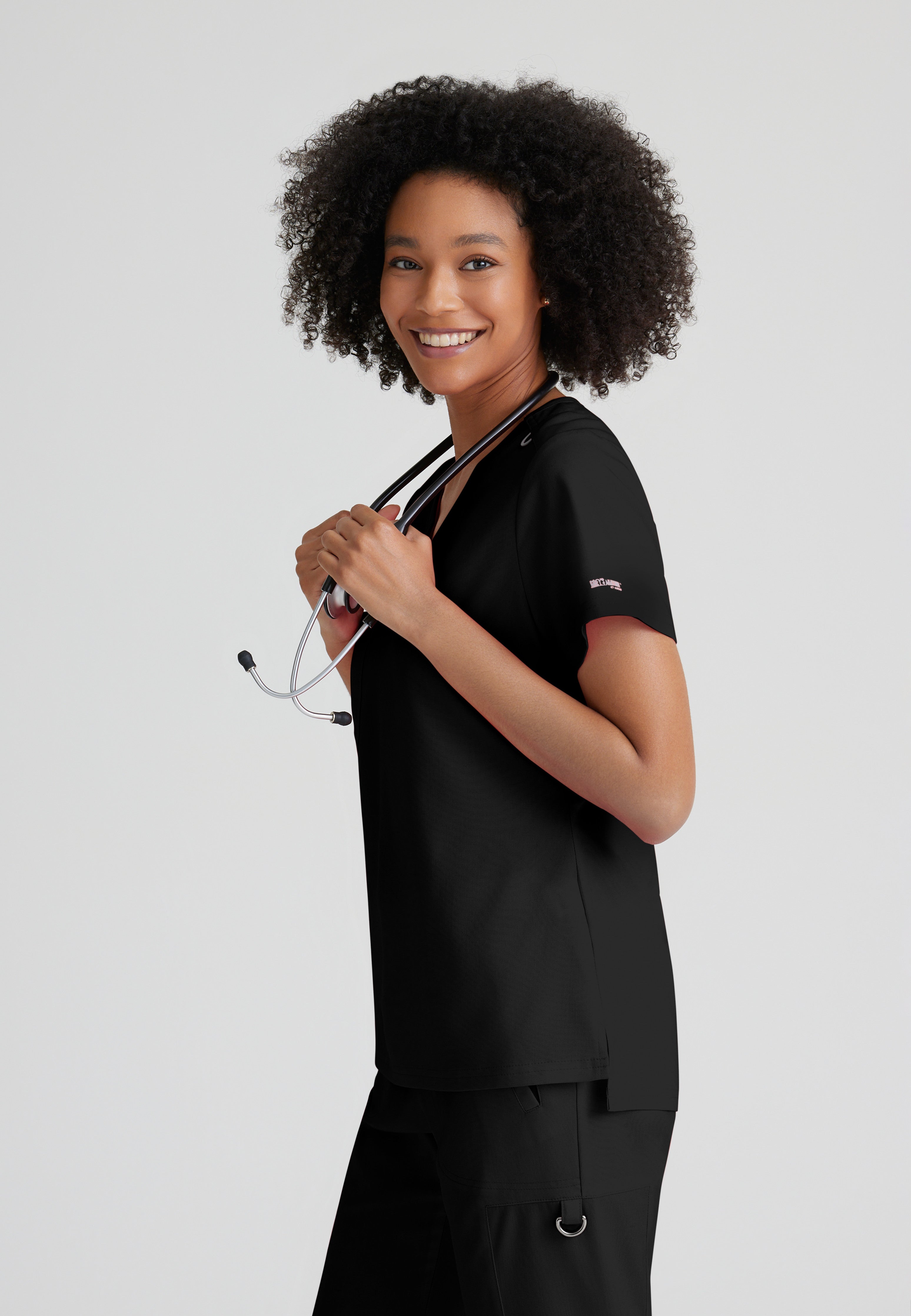 Side View of the Bree 1-Pocket Tuck-In Scrub Top in Black from Grey's Anatomy™ by Barco Spandex Stretch