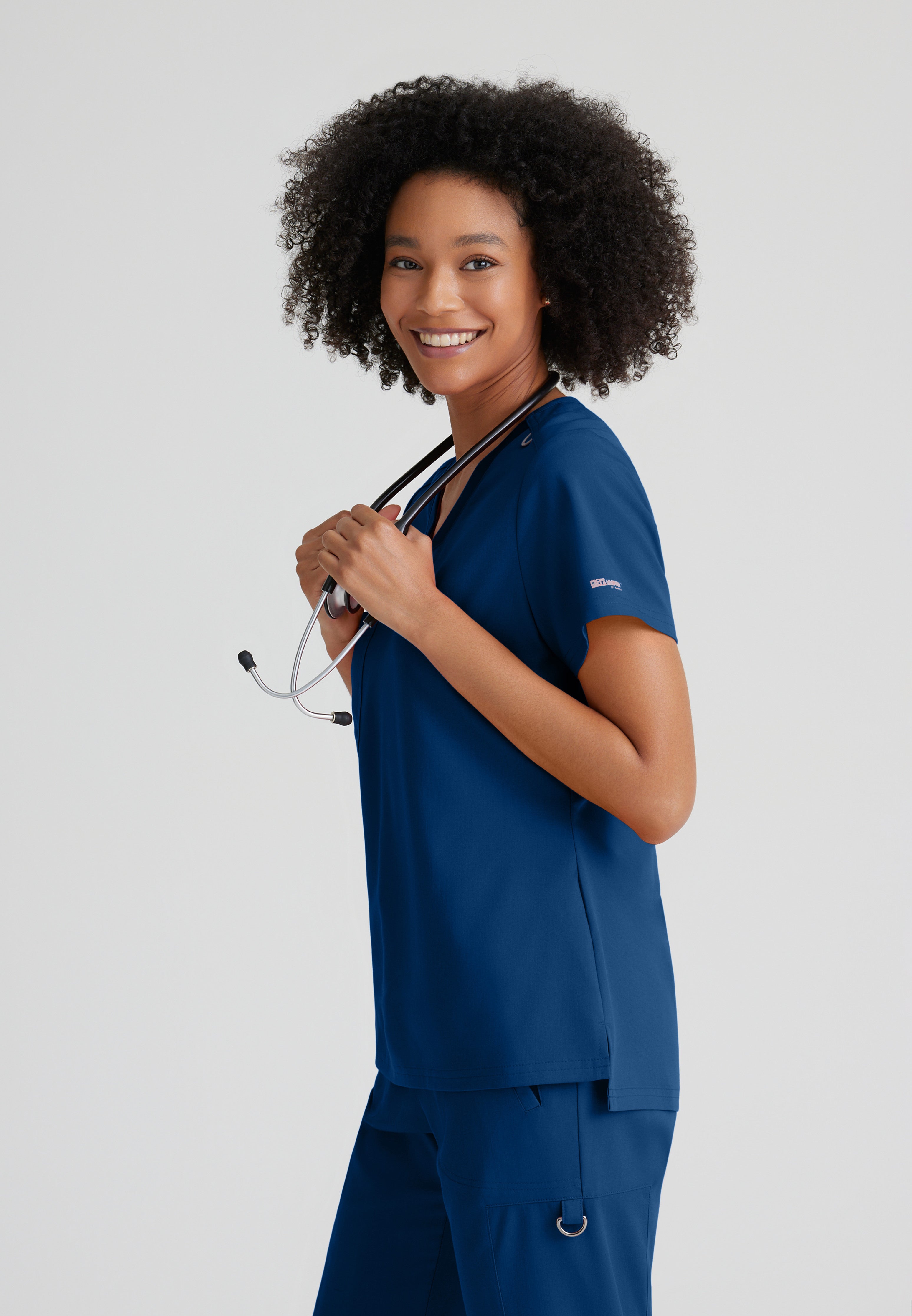 Side View of the Bree 1-Pocket Tuck-In Scrub Top in Indigo from Grey's Anatomy™ by Barco Spandex Stretch