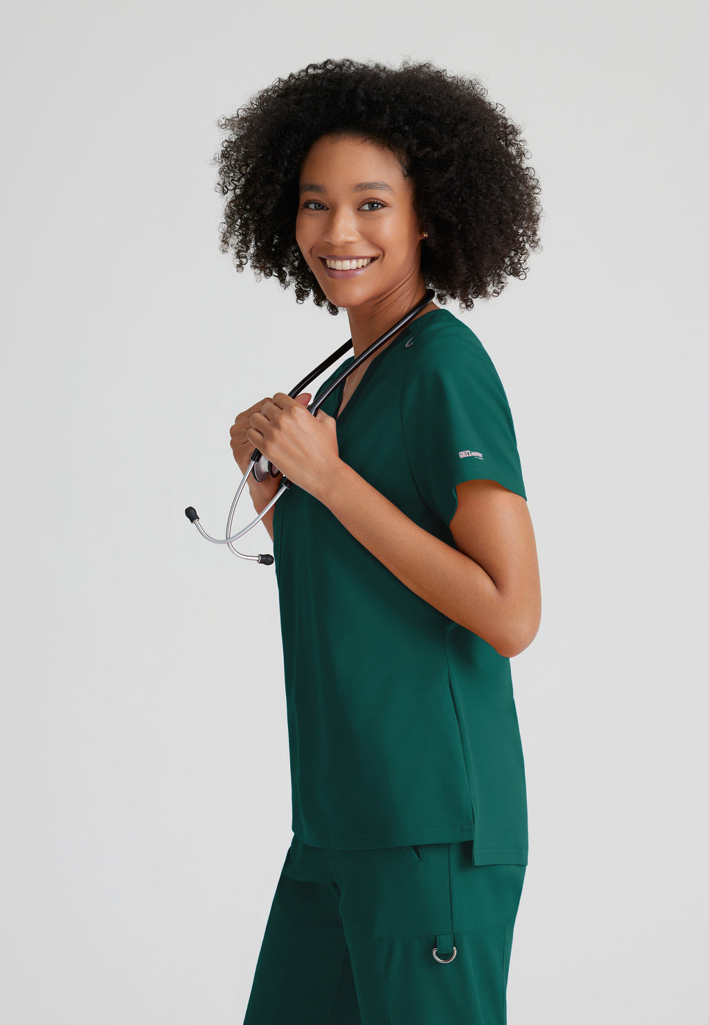 Side View of the Bree 1-Pocket Tuck-In Scrub Top in Hunter Green from Grey's Anatomy™ by Barco Spandex Stretch