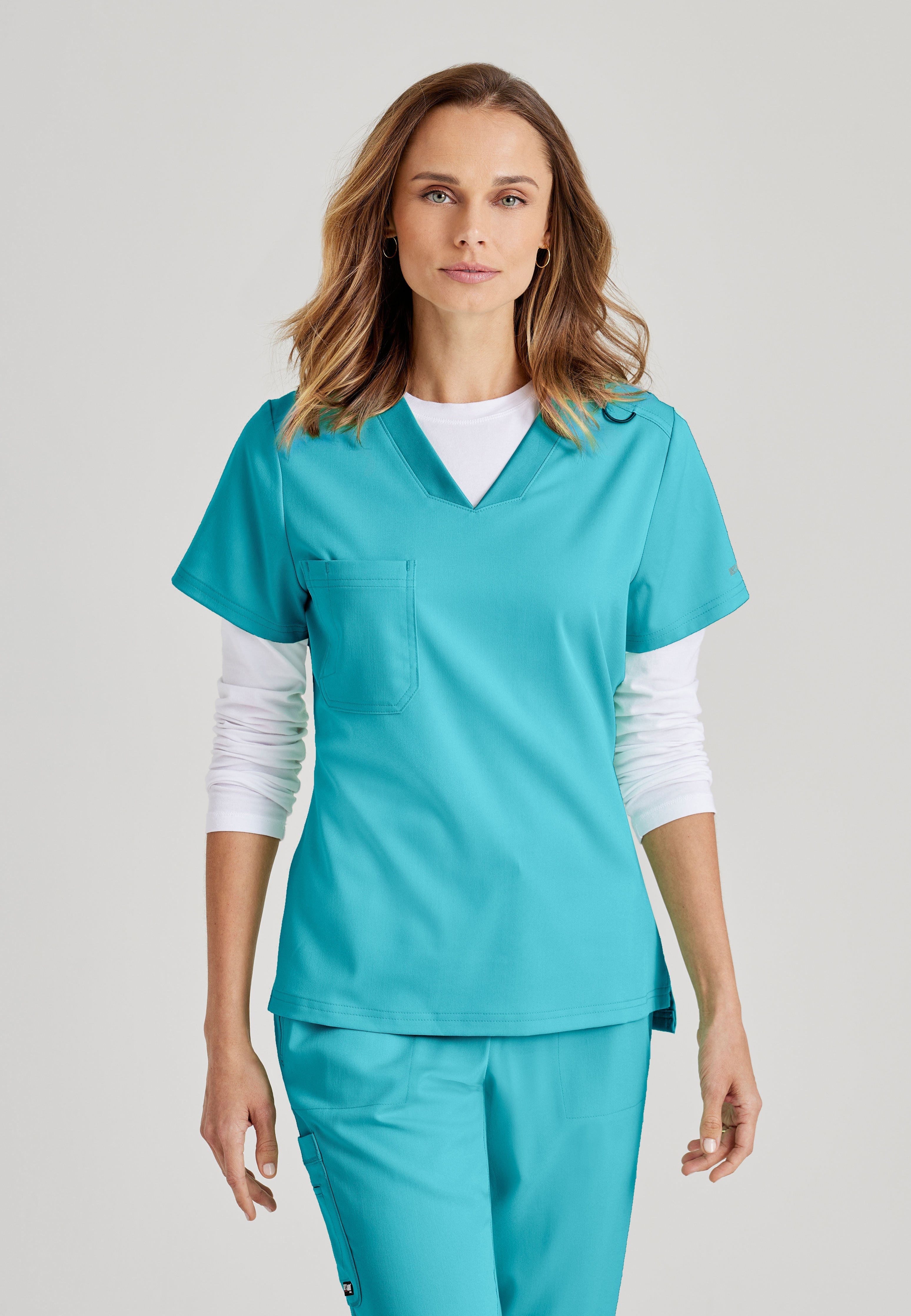 Grey's Anatomy Spandex-Stretch women's teal V-neck scrub top. Chest pocket. Badge loop. Split hem. Moisture-wicking stretch fabric.