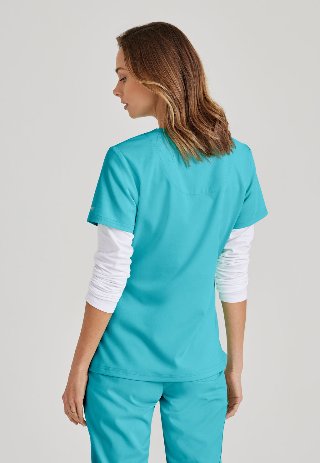 Grey's Anatomy Spandex-Stretch women's teal V-neck scrub top. Chest pocket. Badge loop. Split hem. Moisture-wicking stretch fabric.