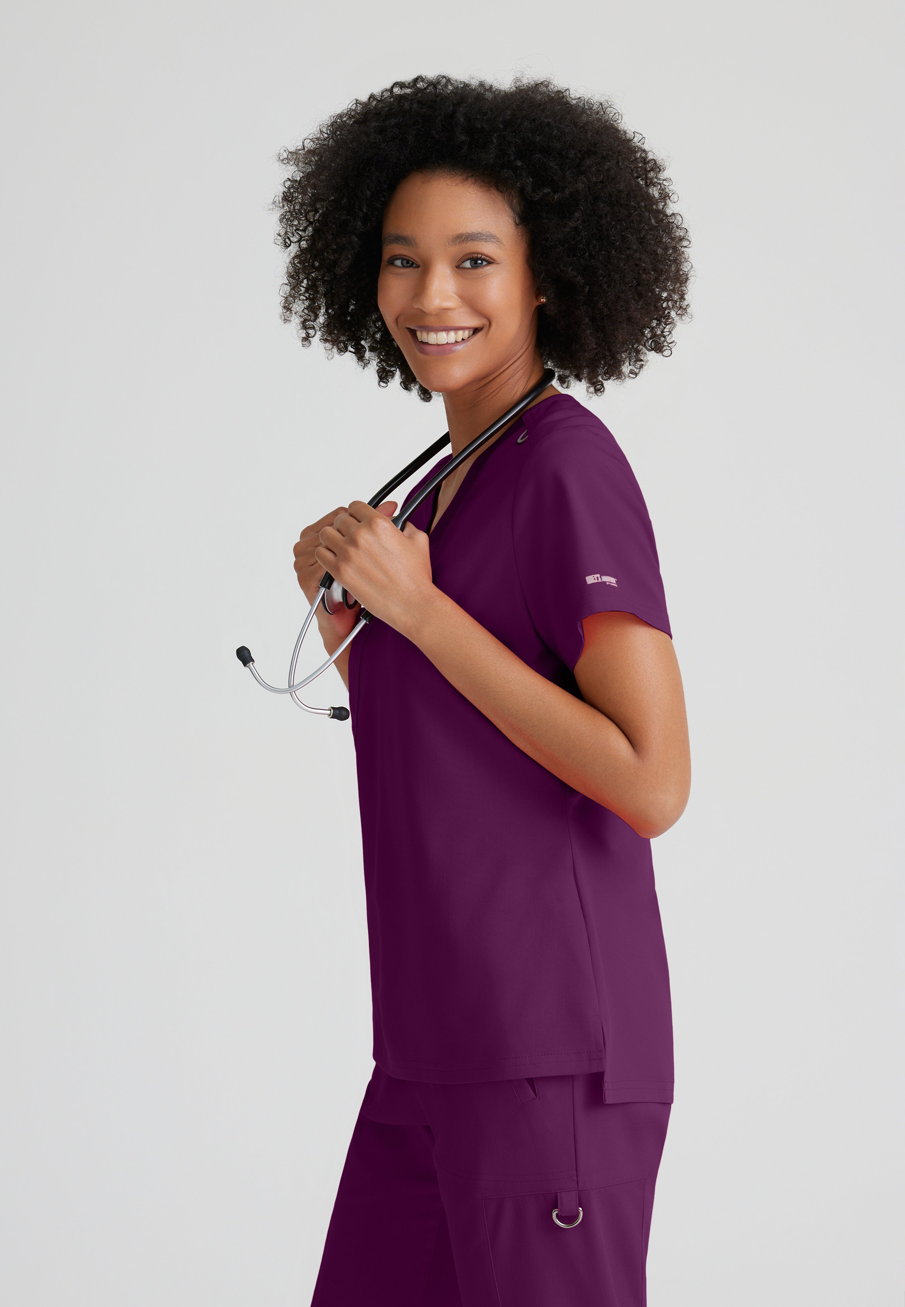 Side View of the Bree 1-Pocket Tuck-In Scrub Top in Wine from Grey's Anatomy™ by Barco Spandex Stretch